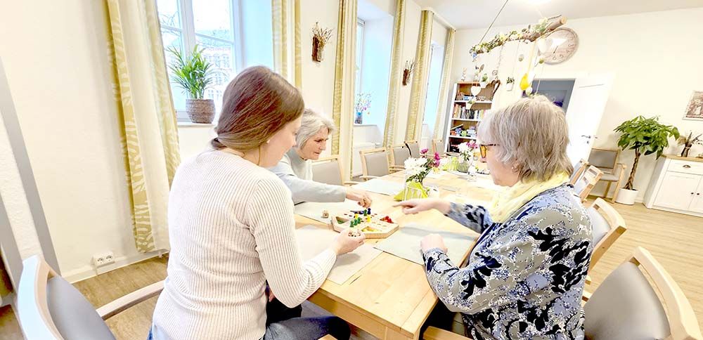 Drei Frauen sitzen am Tisch und spielen Mensch-ärgere-dich-nicht