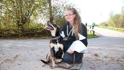 Malteser Besuchsdiensthelferin kniet neben Hund