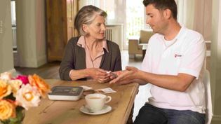 Ein Mitarbeiter der Malteser erklärt einer älteren Frau, wie der Malteser Hausnotruf funktioniert.