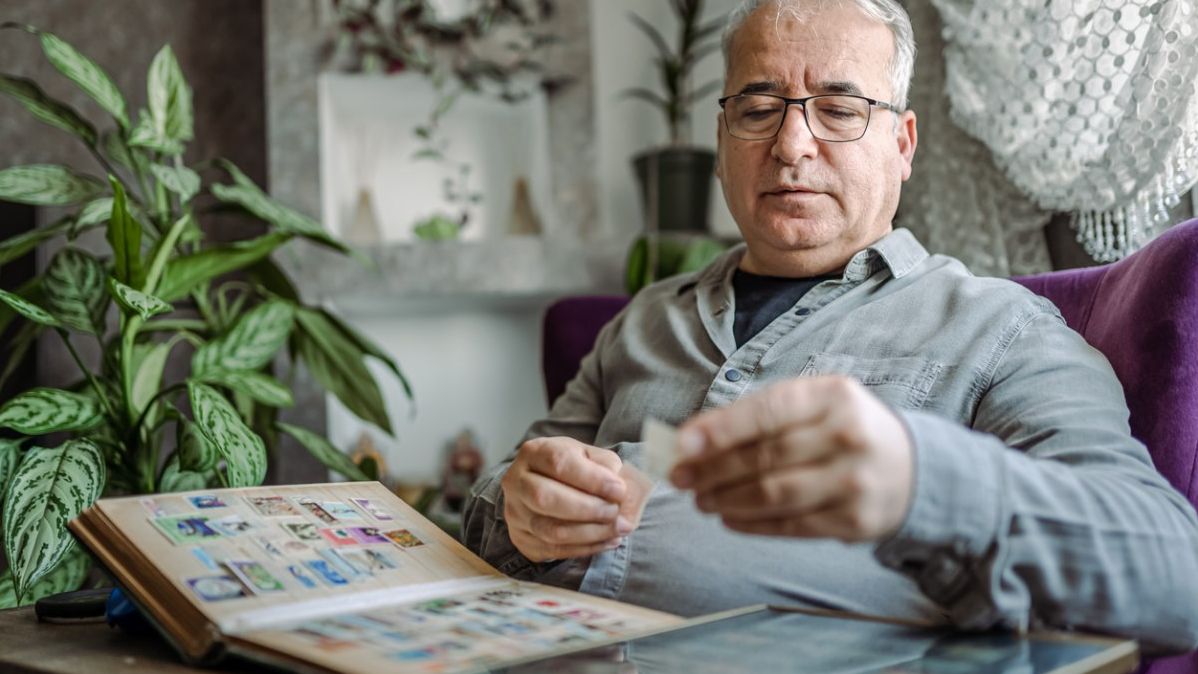 Ein älterer Mann sortiert seine Briefmarkensammlung.