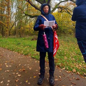 Eine Frau steht auf einem Wanderweg. Sie hält ein Blatt Papier.