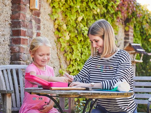 Ein Mädchen und eine junge Frau sitzen an einem Tisch