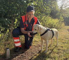 Eine Malteserin gibt einen Rettungshund zu trinken