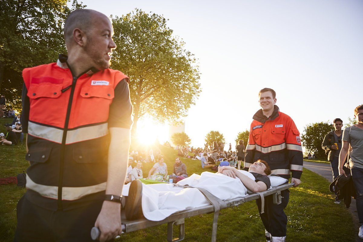 Zwei Malteser Sanitäter schieben einen Patienten auf einer Trage.