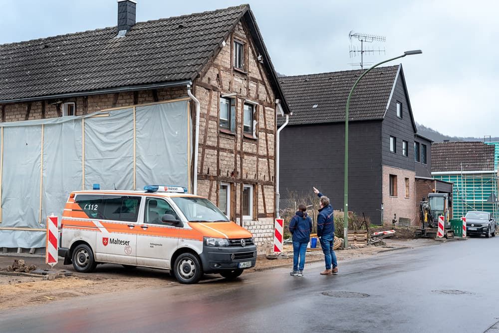 Renovierungsbedürftiges Haus mit einem Malteser Auto davor.