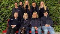 Gruppenfoto von neun Personen und einem Hund.