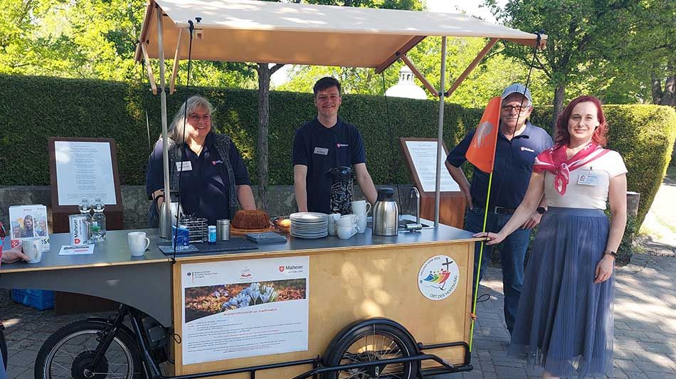 Zwei Männer und zwei Frauen stehen vor einem mobilen Café