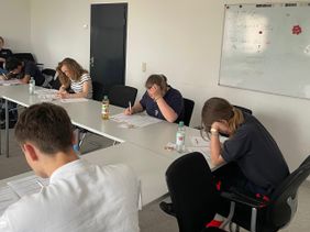 Auf dem Bild sind die Teilnehmenden zu sehen, wie sie die schriftliche Prüfung schreiben