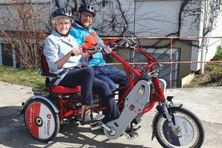 Ein Malteser Helfer fährt mit einer Seniorin Dreirad-Tandem.