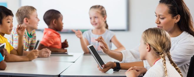 Eine Frau erklärt einem Mädchen etwas an einem Tablet.