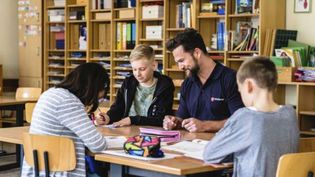 Mitarbeiter unterstützt Kind in Schule