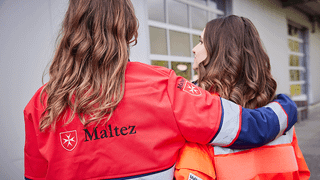 Zwei Frauen aus dem Malteser Volunteers-Programm umarmen sich. 