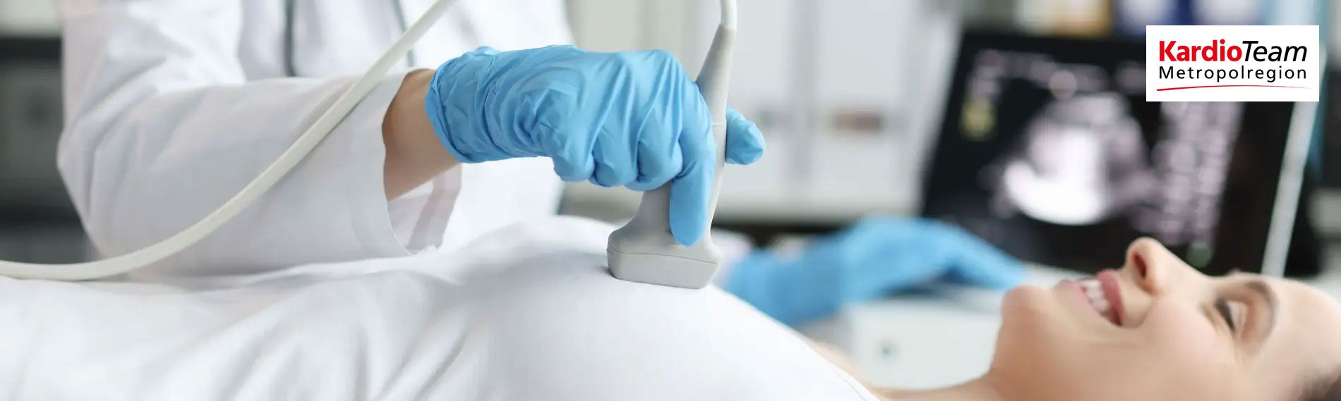Hand mit blauem Handschuh führt Ultraschalluntersuchung am Bauch einer Patientin durch.