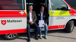 Zwei Männer sitzen bei geöffneter Seitentür in einem Malteser Rettungswagen.