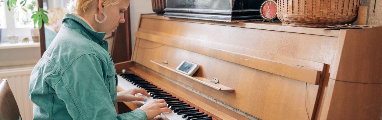 Junge blonde Frau spielt auf einem alten Klavier