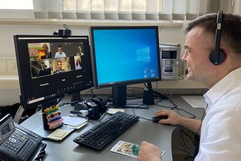 Arzt mit Headset nimmt an einer Videokonferenz am Computer teil.