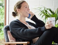 Eine junge Frau sitzt im Sessel und telefoniert