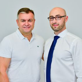Zwei Männer stehen vor einer Wand.