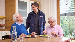 Malteser Mitarbeiterin liefert Essen und spricht mit einem Ehepaar