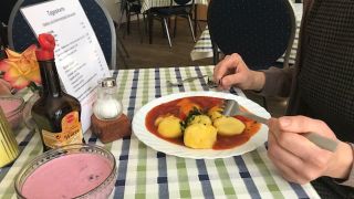 Nahaufnahme eines gefüllten Tellers und Händen, die Messer und Gabel halten