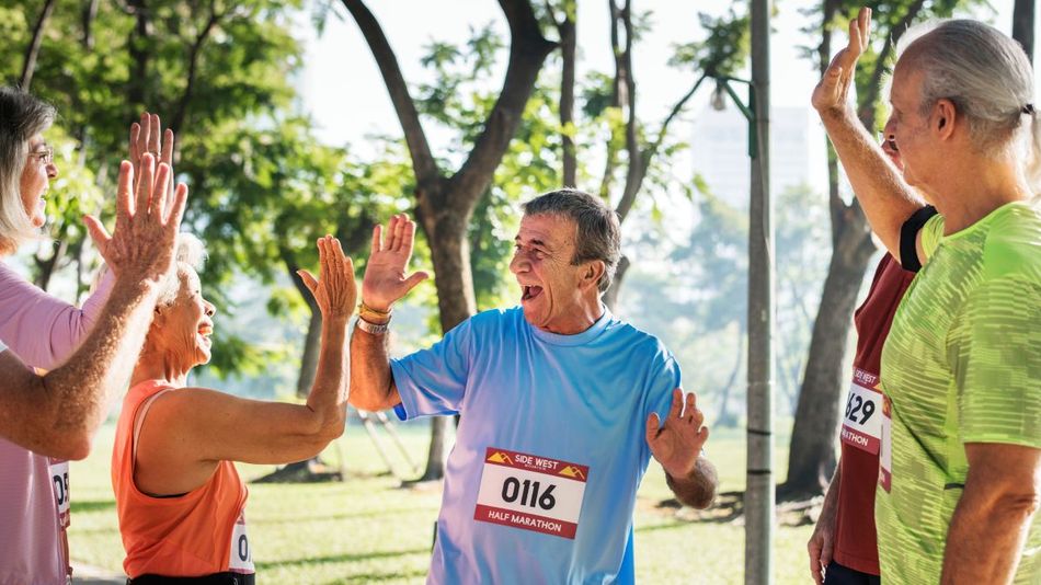 Eine Gruppe aus Läuferinnen und Läufern höheren Alters klatscht einander ab. 