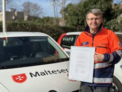 Malteser Mitarbeiter zeigt stolz seine Auszeichnung.