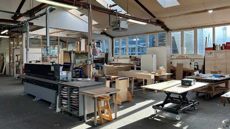 Eine Arbeitshalle mit Werktischen und Maschinen.