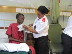 A nurse cares for a seated patient in the hospice.
