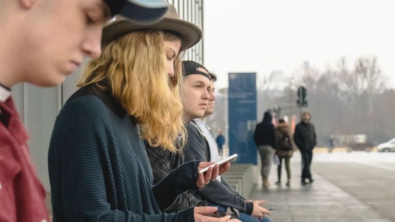 Junge Menschen sitzen auf einer Bank in grauer Stadtkulisse 