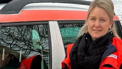 Eine Frau in Malteser Kleidung vor einem Malteser Dienstauto