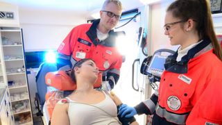 Malteser Mitarbeiter versorgen eine Frau im Rettungswagen.