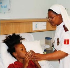 A religious sister gives Bongiwe a drink in her hospice bed; original photograph from newsletter no. 35 (2016), page 7.