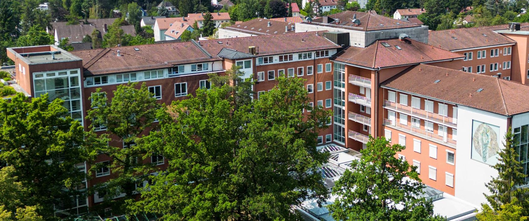 Luftaufnahme des Malteser Waldkrankenhauses St. Marien in Erlangen, umgeben von Bäumen und Wohnhäusern.