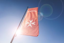 Rote Malteser Flagge mit Sonne im Hintergrund
