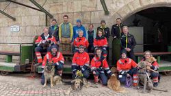 Männer und Frauen, teilweise in Malteser Einsatzkleidung, stehen mit mehreren Hunden vor dem Salzbergwerk Berchtesgaden.