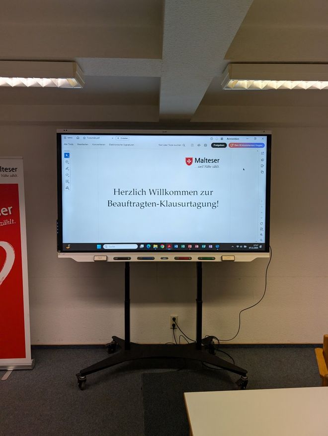 Smartboard im Tagungsraum mit der Begrüßung "Herzlich willkommen zur Beauftragten-Klausurtagung"