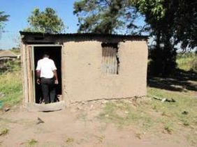 A small hut with an open door in a rural setting.