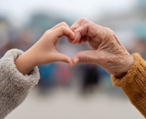 Eine junge und eine alte Hand zeigen gemeinsam ein Herz