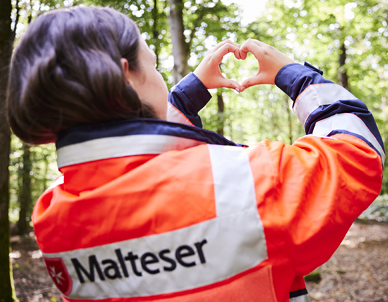 Frau im Wald macht ein Herz