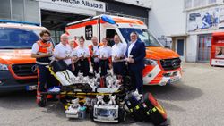 Das Foto zeigt v.l.n.r. die Rettungskräfte Luca Graziano, Josef Ibach, Lena Schwaiger, Nicole Konzelmann, Johannes Pfister, Svenja Tschuk, mit Dienststellenleiter Thomas Linhart und Arndt Ständer, Vorsitzender der Bezirksvereinigung der Volks- und Raiffeisenbanken im Zollernalbkreis. Die Gruppe steht vor der Rettungswache in Albstadt-Tailfingen. Im Hintergrund sind ein Krankentransportwagen (KTW) und ein Rettungswagen (RTW) zu sehen. Im Vordergrund steht eine Fahrtrage auf der viele Plüsch-Elefanten sitzen. Vor der Trage steht medizinisches Materiasl.