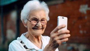 Eine alte Frau blickt auf ein Smartphone.