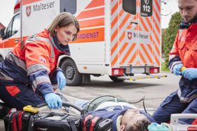 Zwei Einsatzkräfte im Rettungsdienst versorgen einen Patienten