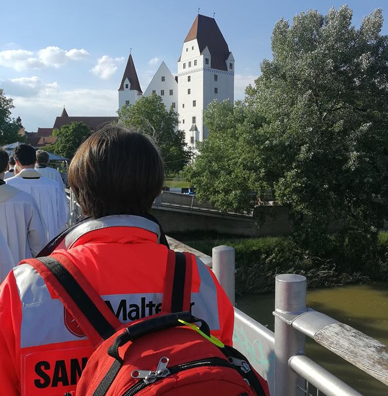 Malteser Sanitäterin bei einer Prozession von hinten fotografiert.