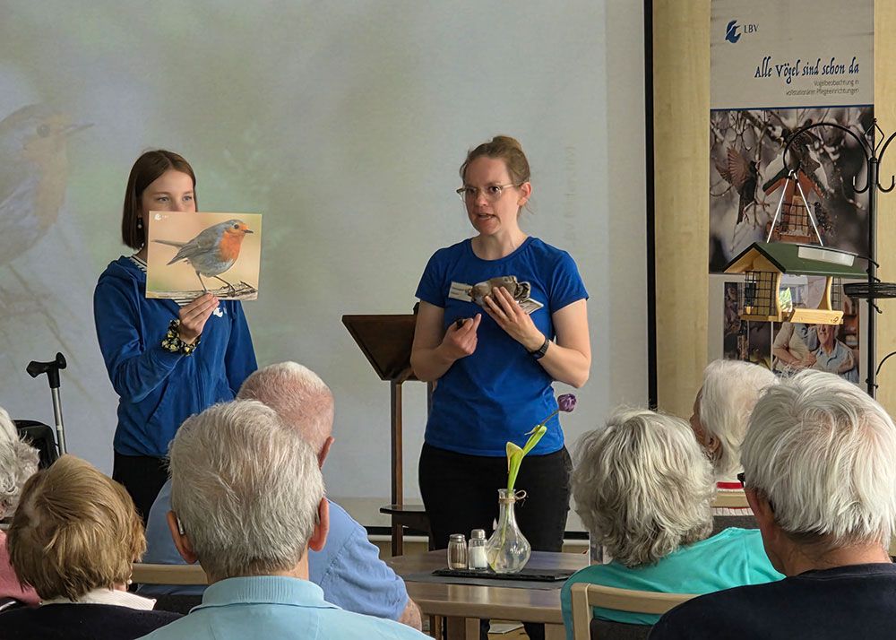 Referentin Lisa-Sophie Scheuer vom Landesbund für Vogel- und Naturschutz (LBV) erklärt den Seniorinnen und Senioren bei einem Vortrag, welche Vogelarten zur Futterstation kommen.