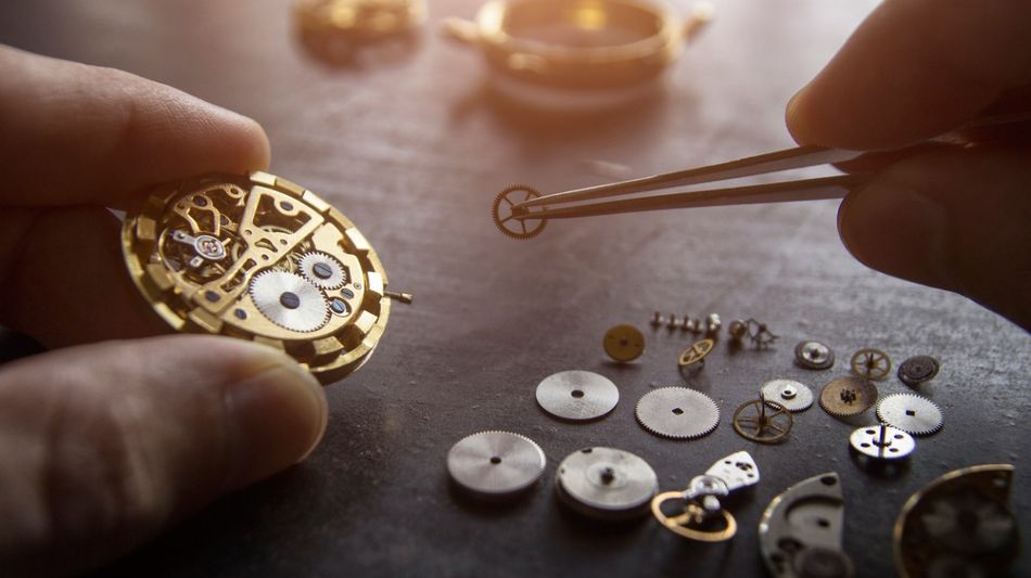 Ein mechanisches Uhrwerk wird mit Werkzeug auseinandergebaut.