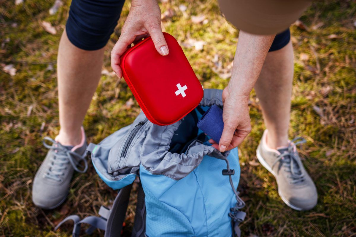 Eine Frau verstaut einen Erste-Hilfe-Kasten in einem Wanderrucksack