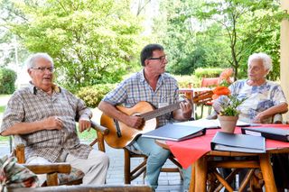 Begleiter des sozialen Dienst spielt für die Bewohner Gitarre und alle singen zusammen