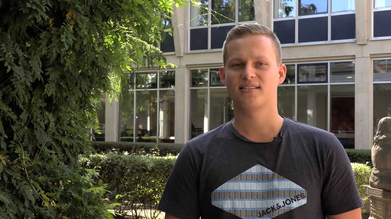 Ein junger Mann, der ehrenamtlich für den Malteser Hospizdienst arbeitet, steht draußen und schaut in die Kamera.