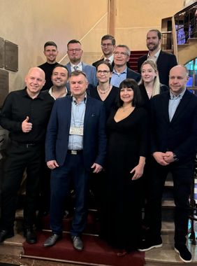 Mehrere Personen in Anzug und Festkleidung stehen auf einer Treppe