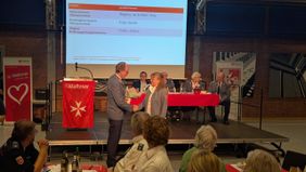 Herr Dr. van Lengerich überreicht einer gewählten Funktionärin einen Blumenstrauß und dankt für das Engagement